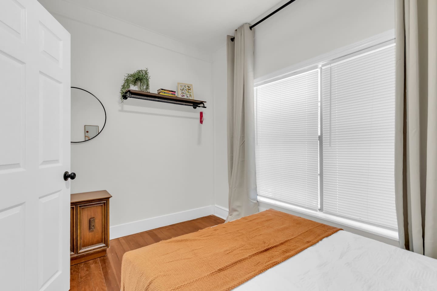 Bedroom with cozy full bed, mirror, clothing rack, hangers and fresh decor.