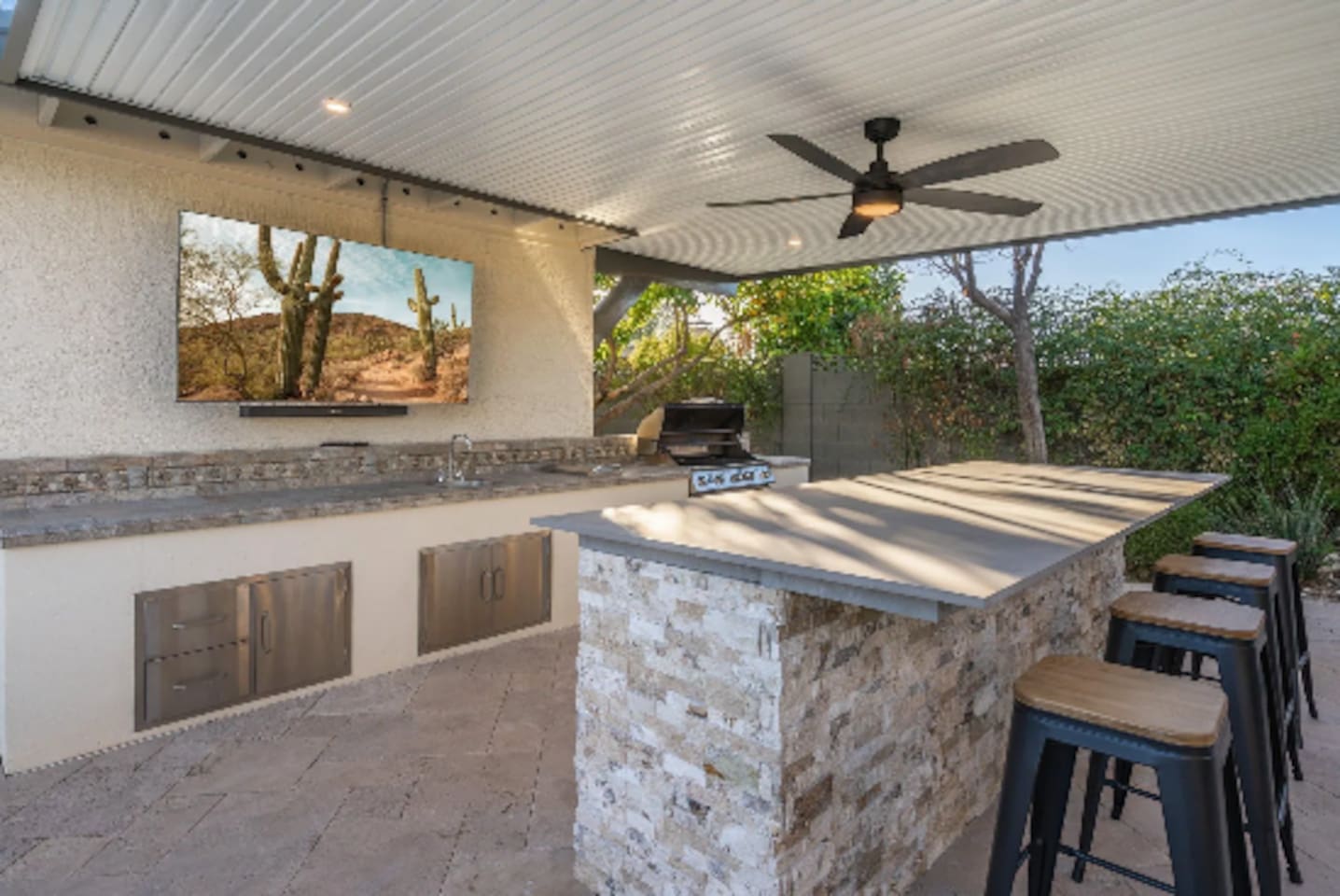 A fully equipped outdoor kitchen turns grilling into the main event, with bar seating and a mounted TV so no one misses the game. Built-in storage keeps everything tucked away and ready to go.
