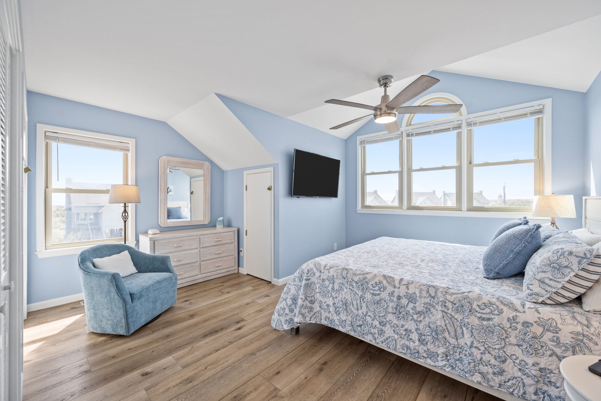 This inviting primary suite offers a plush king bed, coastal décor, ceiling fan, and plenty of space to unwind—perfect for slow mornings and peaceful nights.