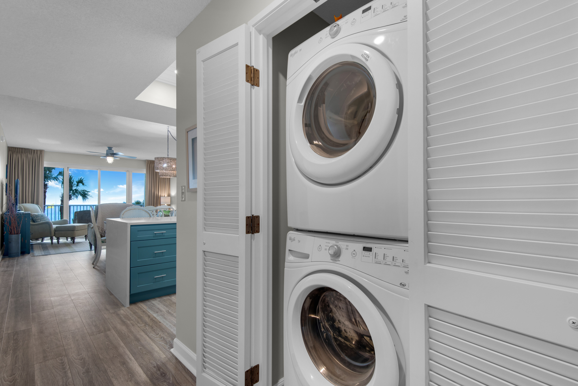 In-unit laundry with Gulf views beyond the living area. Living-room furniture shown has since been replaced.