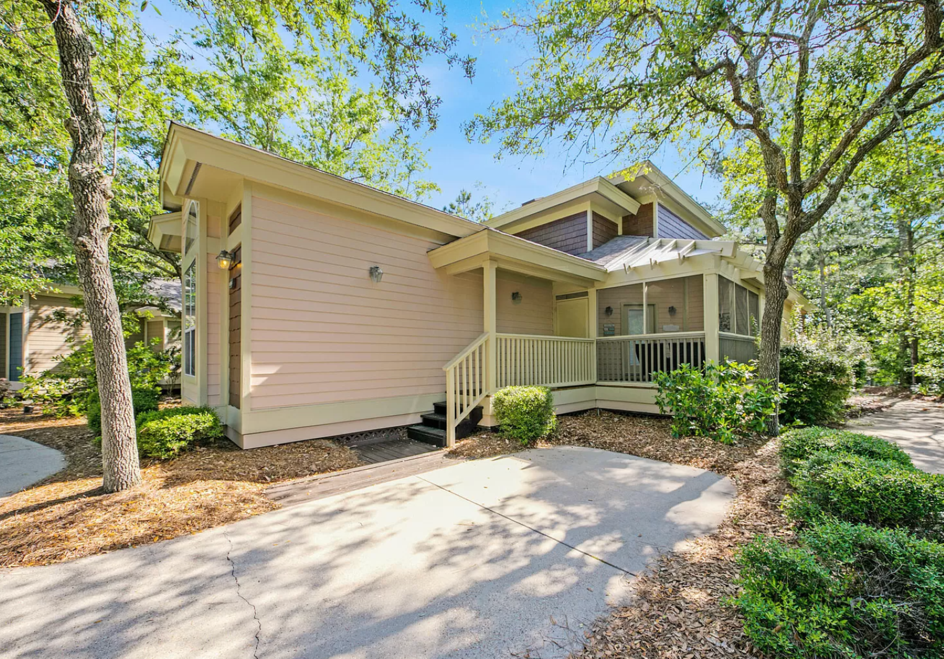 Cozy, sunlit entrance to Bayside Bliss—a charming corner, soft coastal hues, and lush landscaping set the tone for a relaxed.