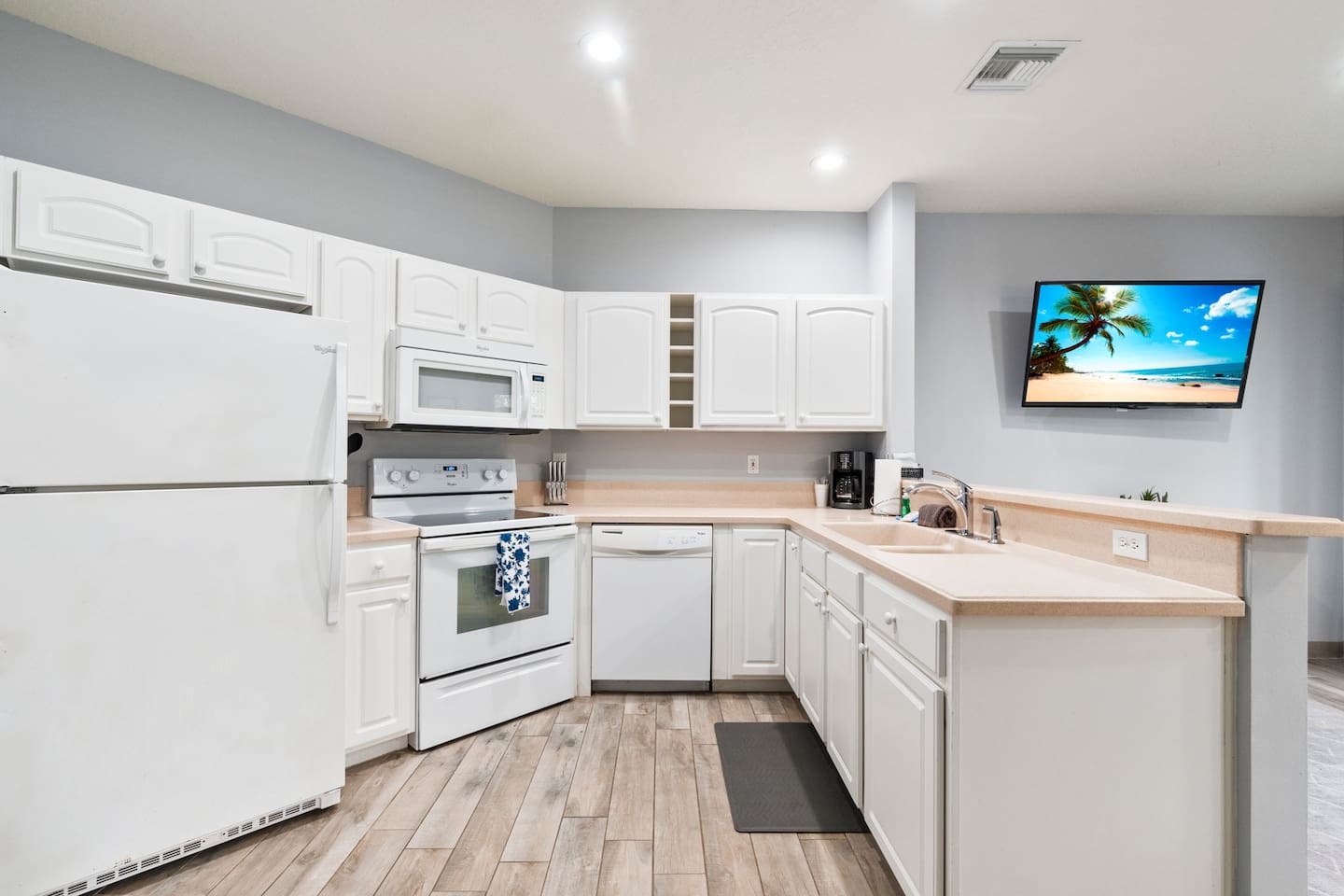 Bright kitchen with white cabinetry, full-size appliances, breakfast bar, and an open layout connecting to the living area.