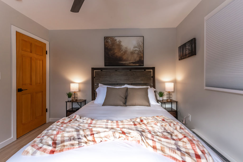 Main level bedroom with a queen sized mattress and side tables. 