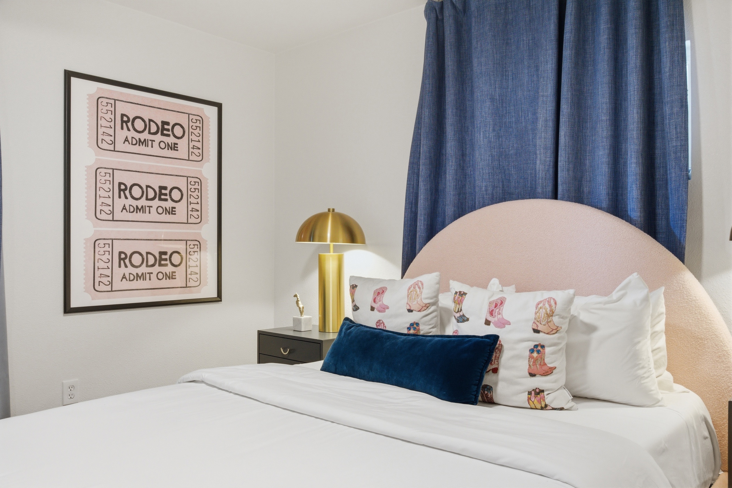 Double bed close-up with decorative pillows and rodeo-themed wall art. Extra pillows and blankets provided. Room-darkening shades and clothing storage included.