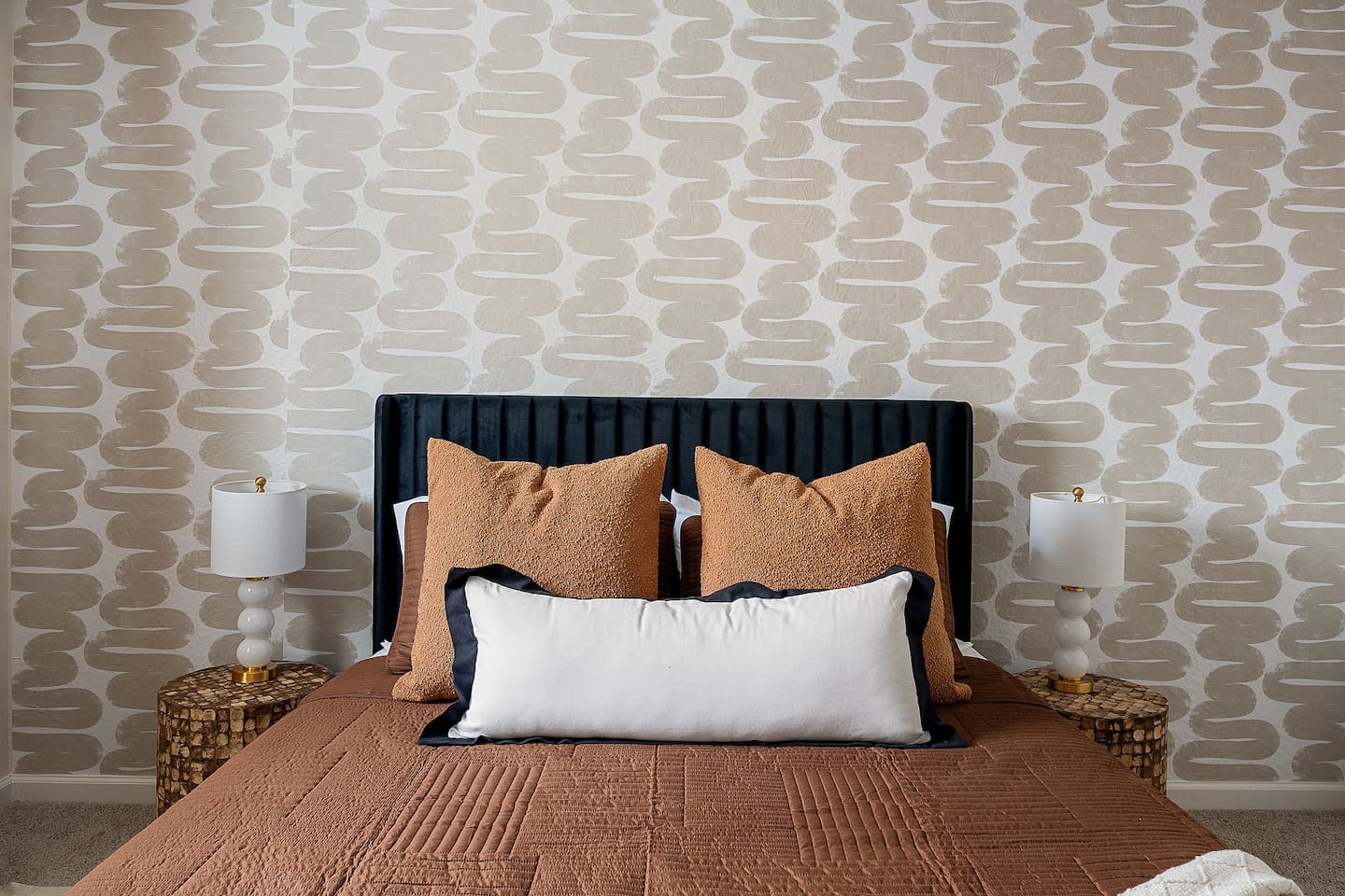 Admire the elegant design of this bedroom, featuring a plush headboard and modern bedside lamps. Perfect for a comfortable and stylish retreat.