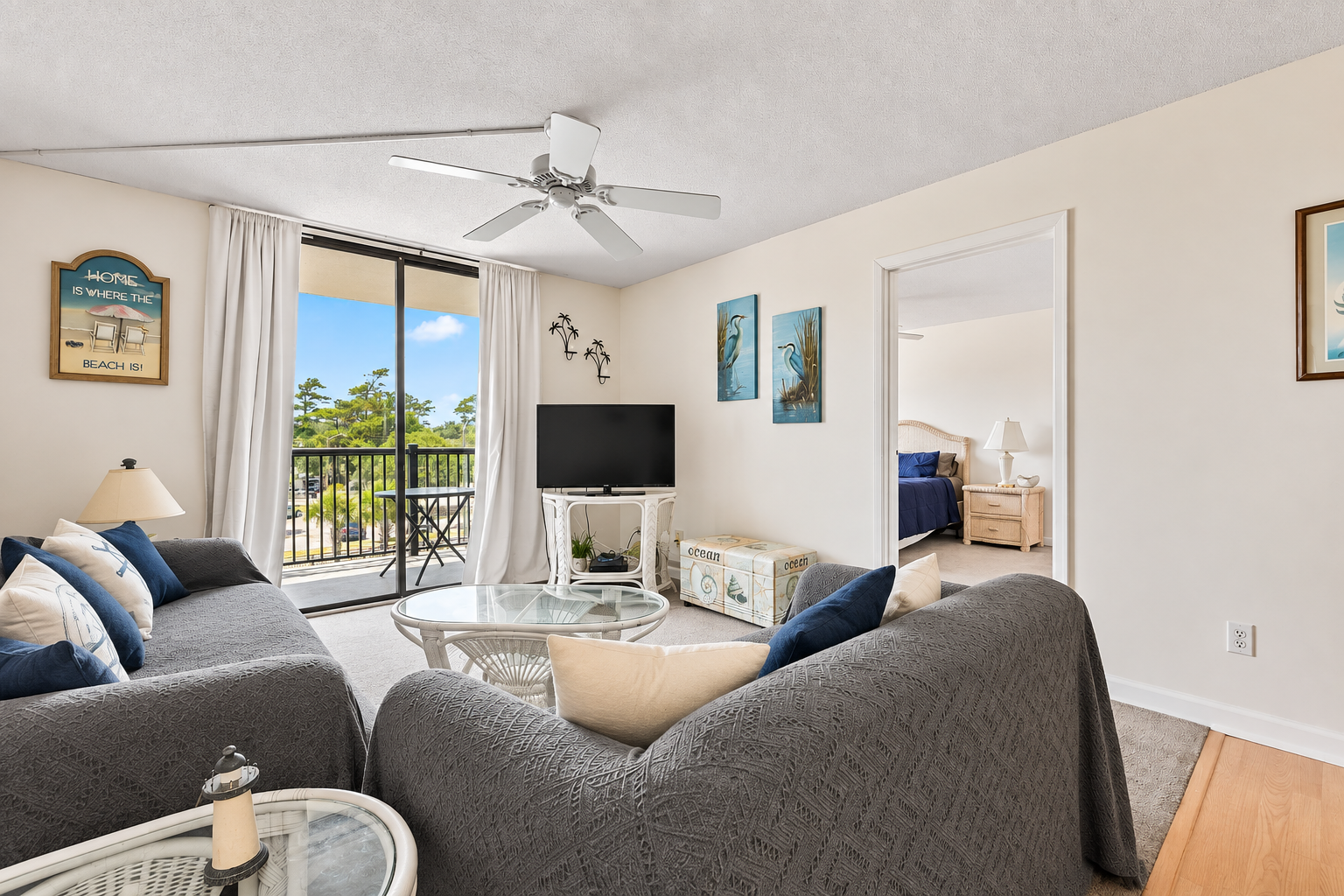 Living room with balcony access, TV,  and beach-style decor