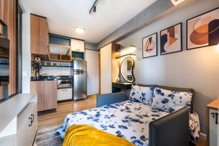Ambiente multifuncional: cozinha completa integrada à sala com sofá-cama montado, ideal para quem busca conforto e praticidade em Pinheiros.