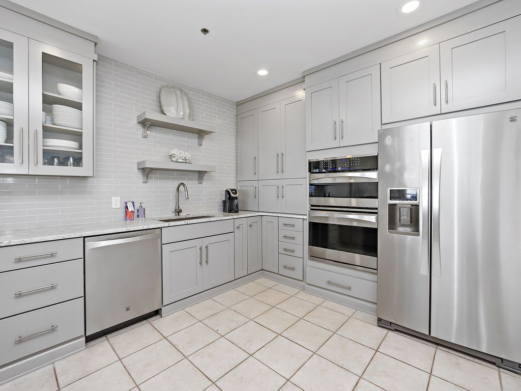 Another view of the kitchen with stainless appliances and Cararra countertops