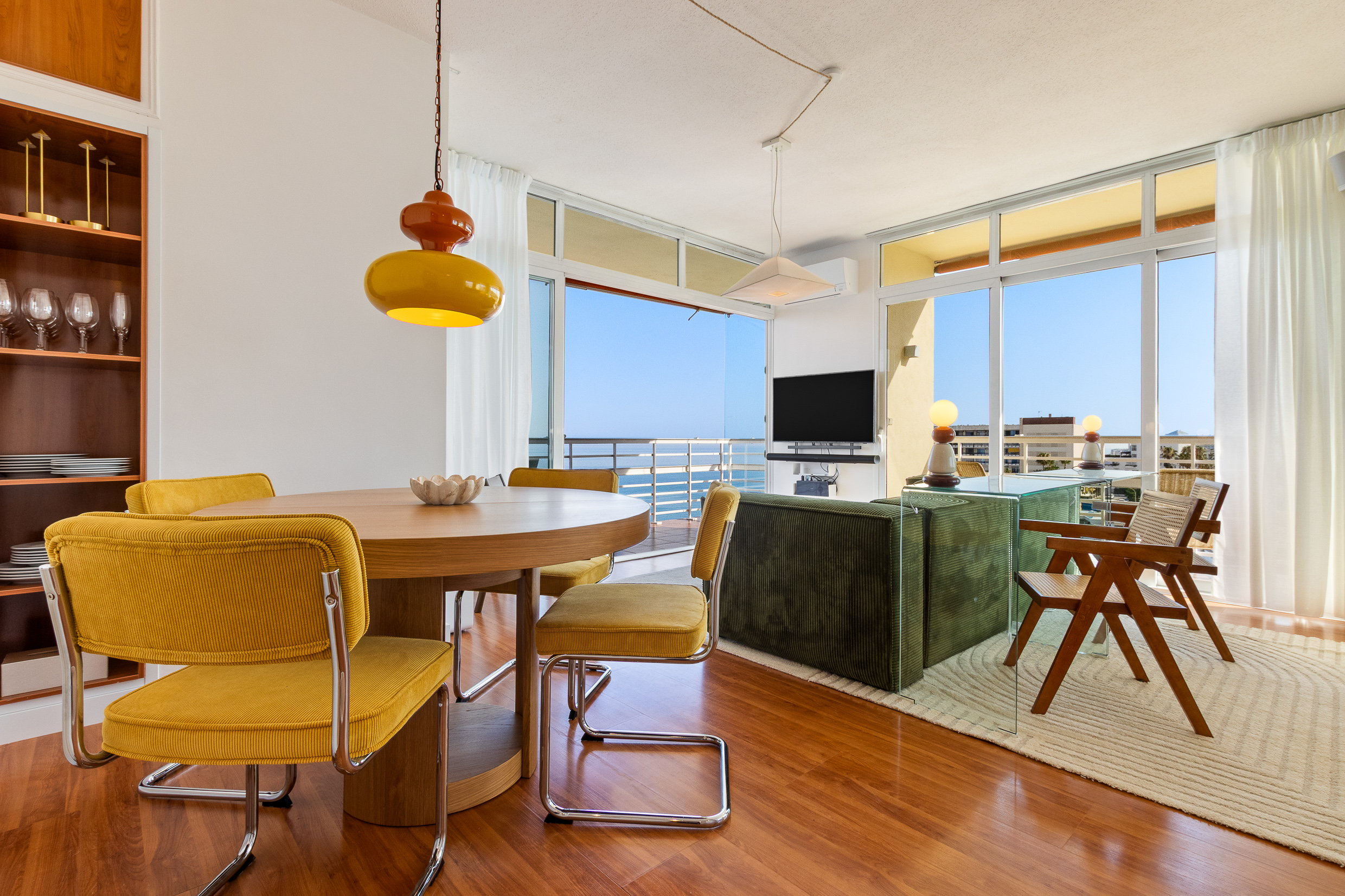 Bright open-plan living and dining area with sea views and balcony access.
