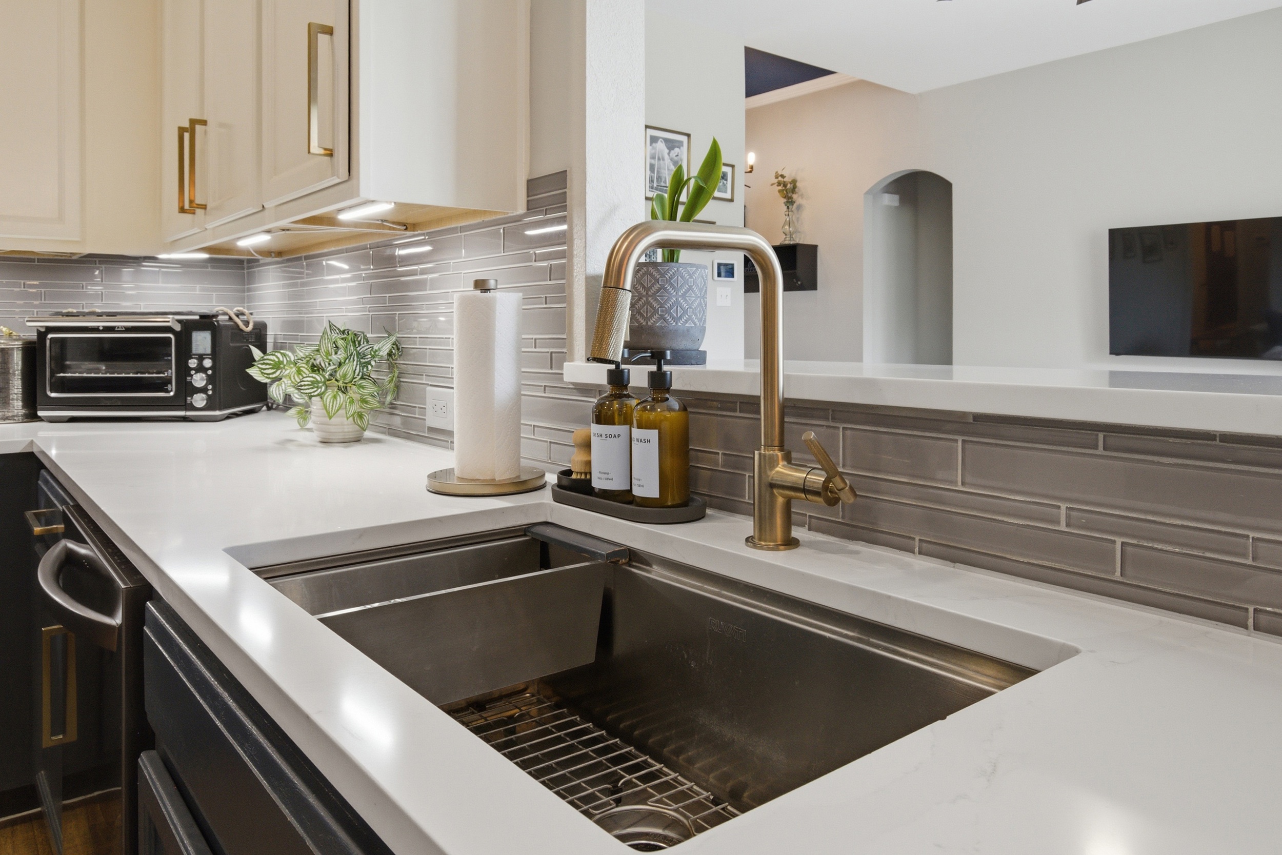 Deep stainless steel Sink with high-arc gold faucet, plenty of counter space, and prep area for cooking.
