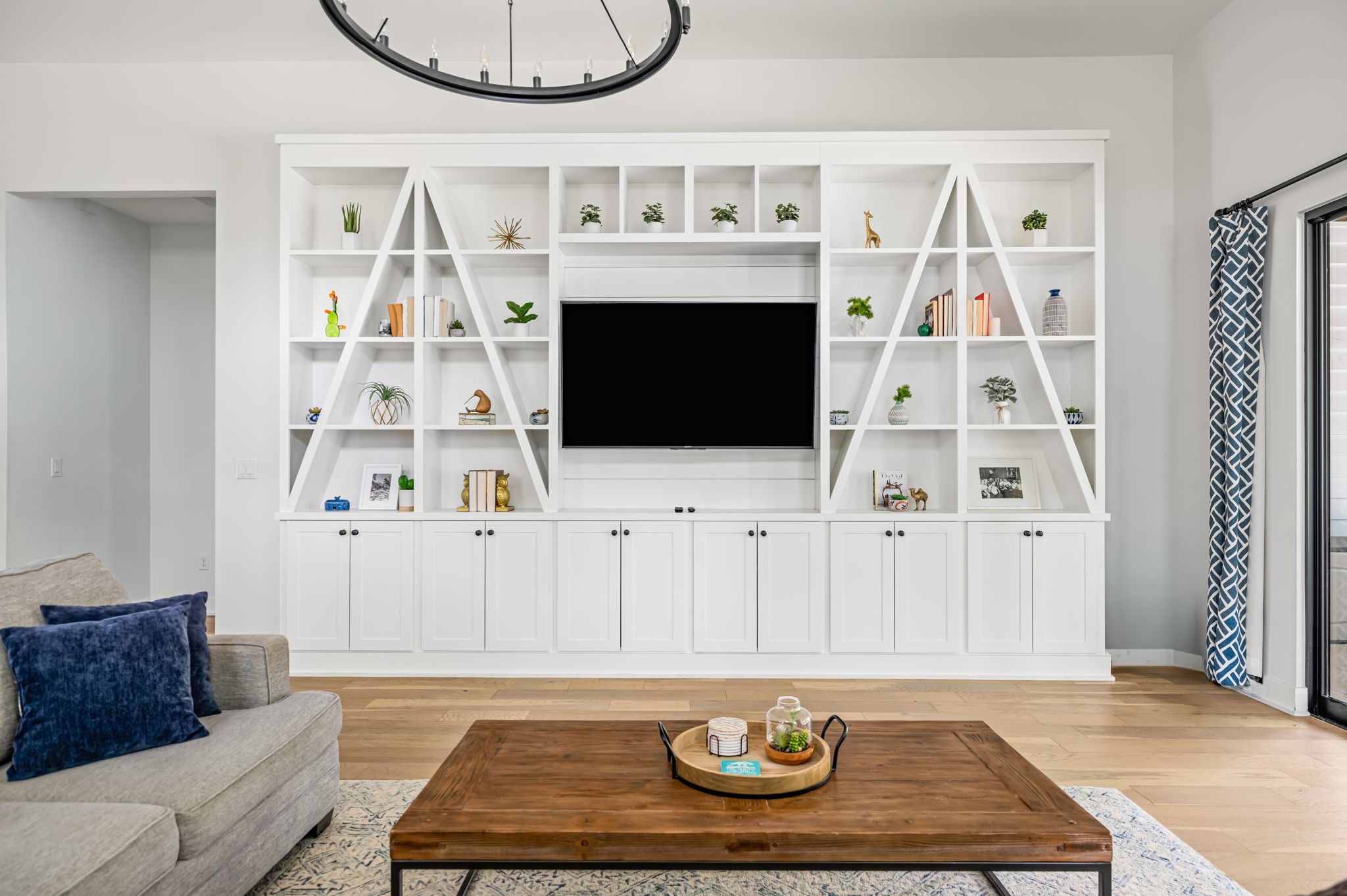 Elegant living room featuring custom built-in shelving, wall-mounted TV, and plush blue and gray seating for cozy movie nights.