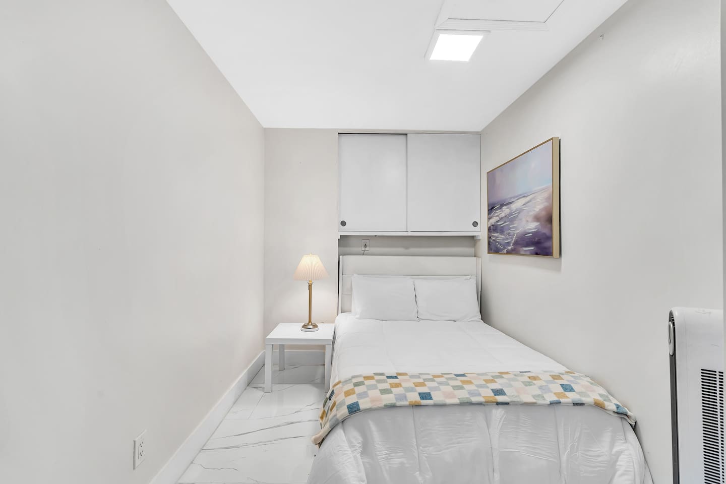 Cozy bedroom with a comfortable bed, bedside table and reading lamp.