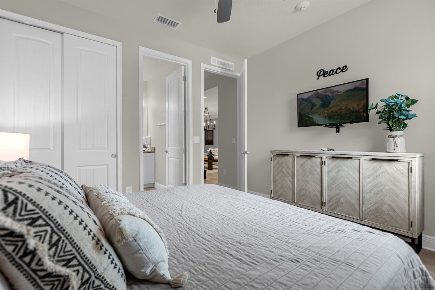 At the center of the room, a cozy bed features a stylish gray headboard, adorned with plush pillows. The bedspread is a soothing shade of pale gray.