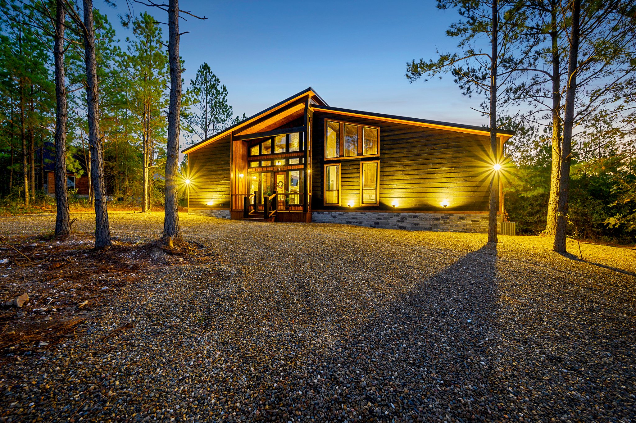 A stunning modern cabin retreat glowing warmly under the forest canopy.