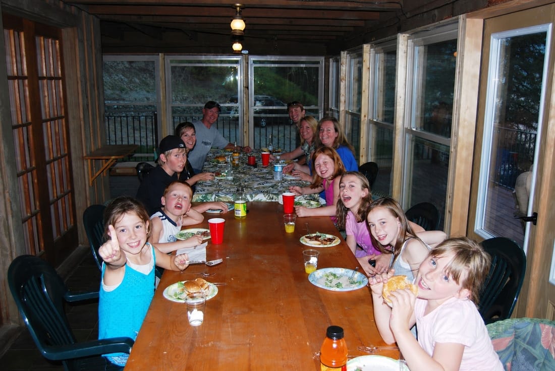 Children and adults gathered around a long dinner table at the lodge