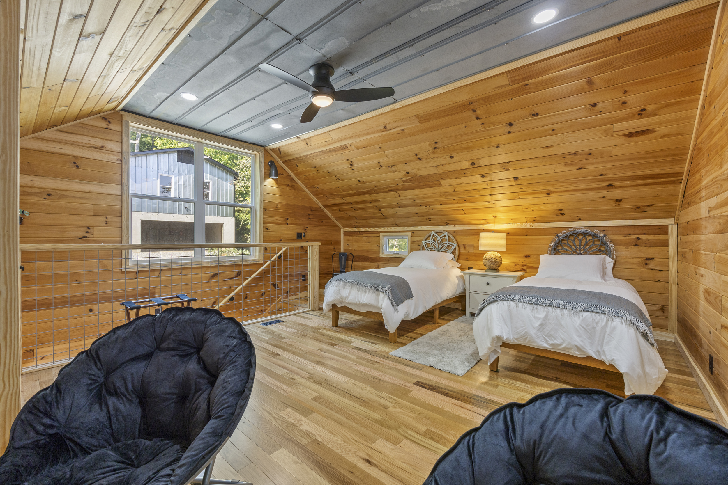 Loft with twin beds under vaulted wood ceilings — a cozy spot for kids or extra guests.