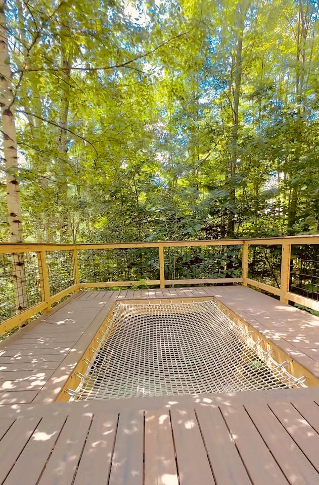 This unique treehouse deck offers a luxurious outdoor experience with an elevated hot tub and XL hammock seamlessly built into the deck floor. Additionally, enjoy the refreshing outdoor shower while surrounded by nature, making it a perfect retreat.