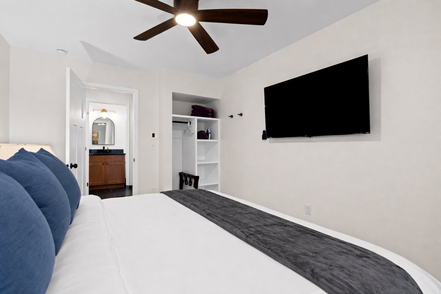 Spacious bedroom retreat with plush bedding, ceiling fan, smart TV, and convenient storage—perfect for relaxing nights and easy mornings.