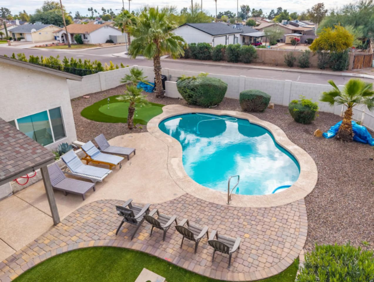 Resort-style backyard with sparkling pool, spa, putting green, and multiple lounging areas.