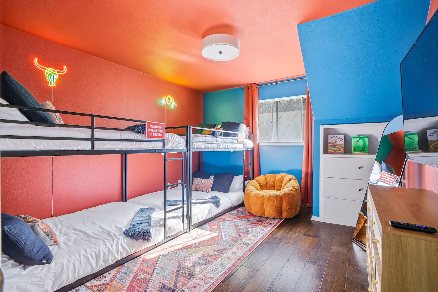 Second-floor bedroom with queen-on-queen bunk beds, Roku TV, and a small kids’ book collection