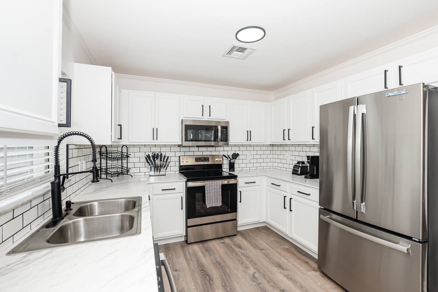 Minimalist all-white interior featuring sleek stainless steel and modern appliances for a clean, contemporary look.