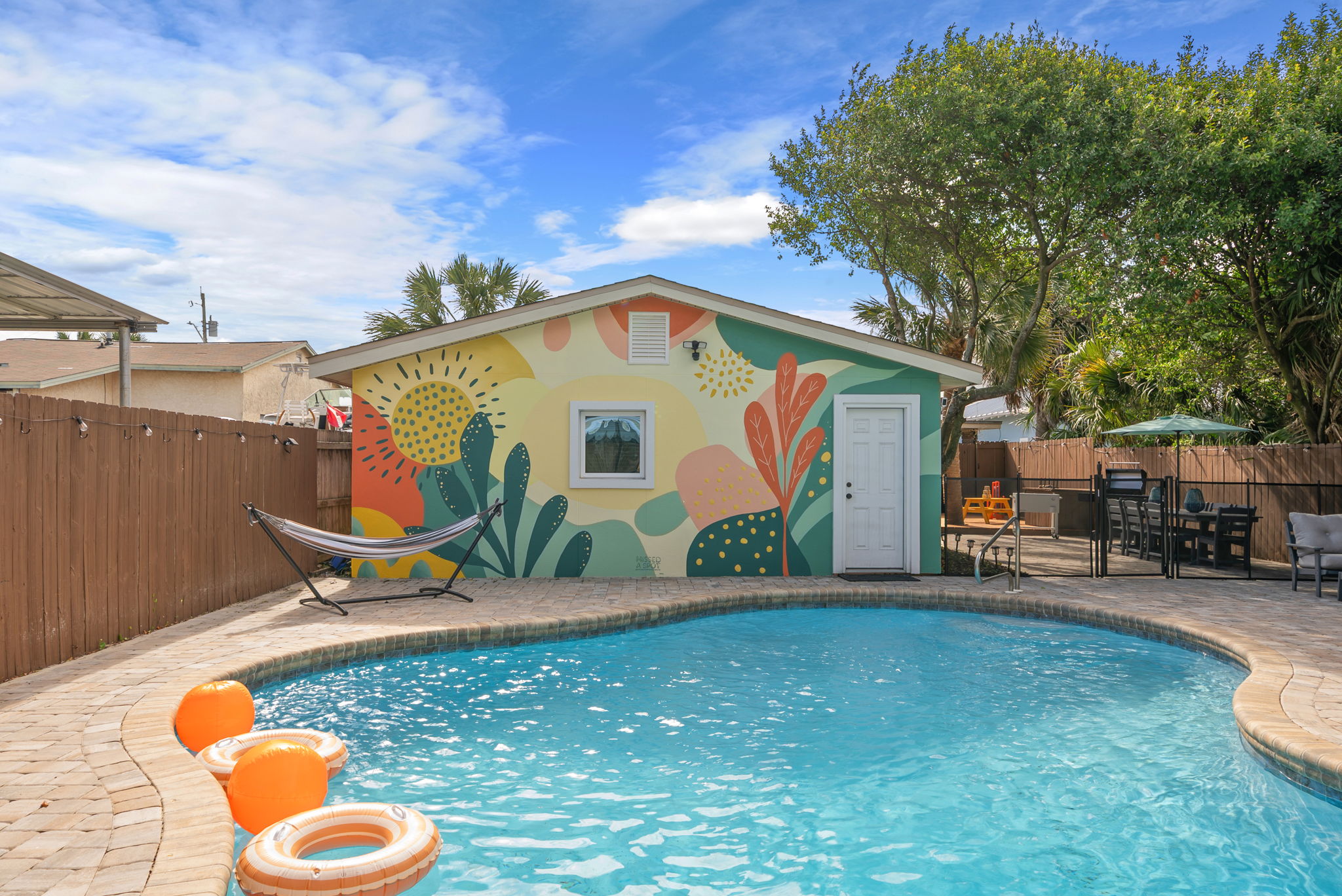 Dive into your private pool the moment you arrive! The freeform backyard oasis is yours all week, with loungers, umbrellas, hammock stand, and a vibrant tropical mural setting the mood.
