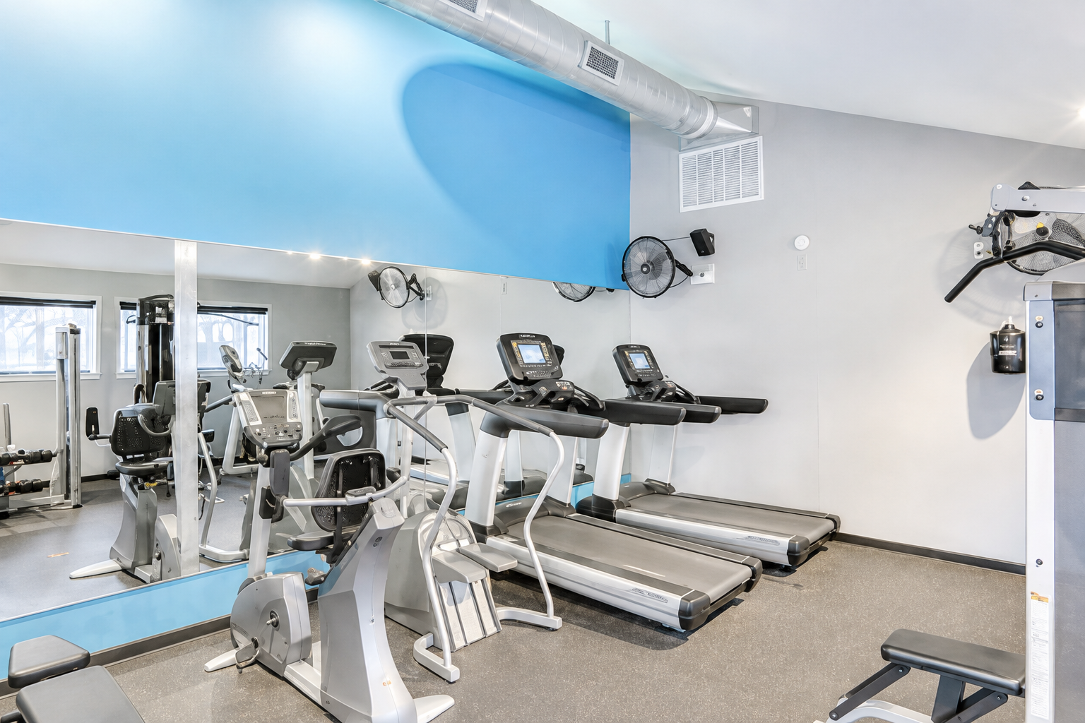 Shared fitness center with cardio equipment, mirrors, and space for a simple workout during your stay.