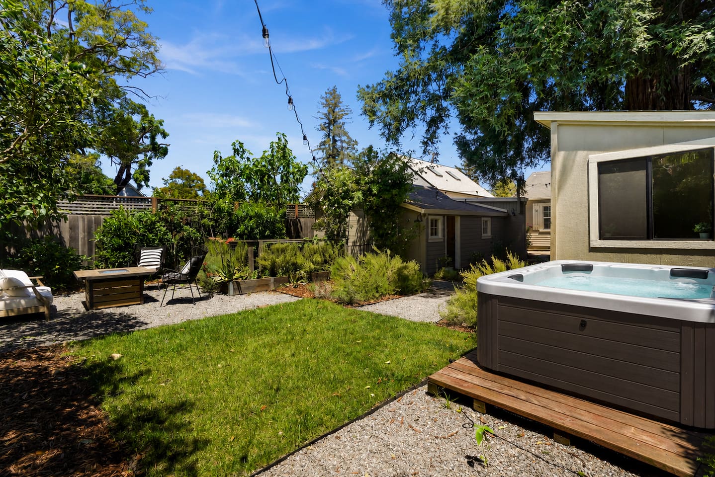 Private backyard retreat featuring a hot tub, fire pit, and multiple outdoor seating areas perfect for relaxing nights.