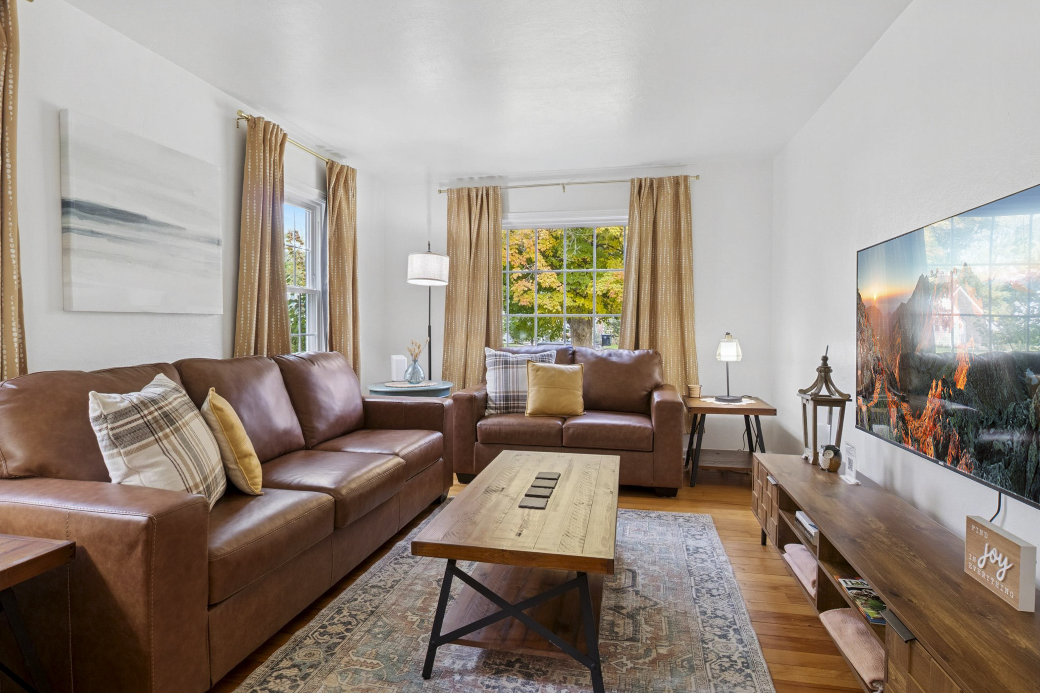 Settle in and stream in style—our South Bend living room features a 65" smart TV, plush seating, accent tables with built-in chargers, and cozy throws and pillows for lounging near Notre Dame.
