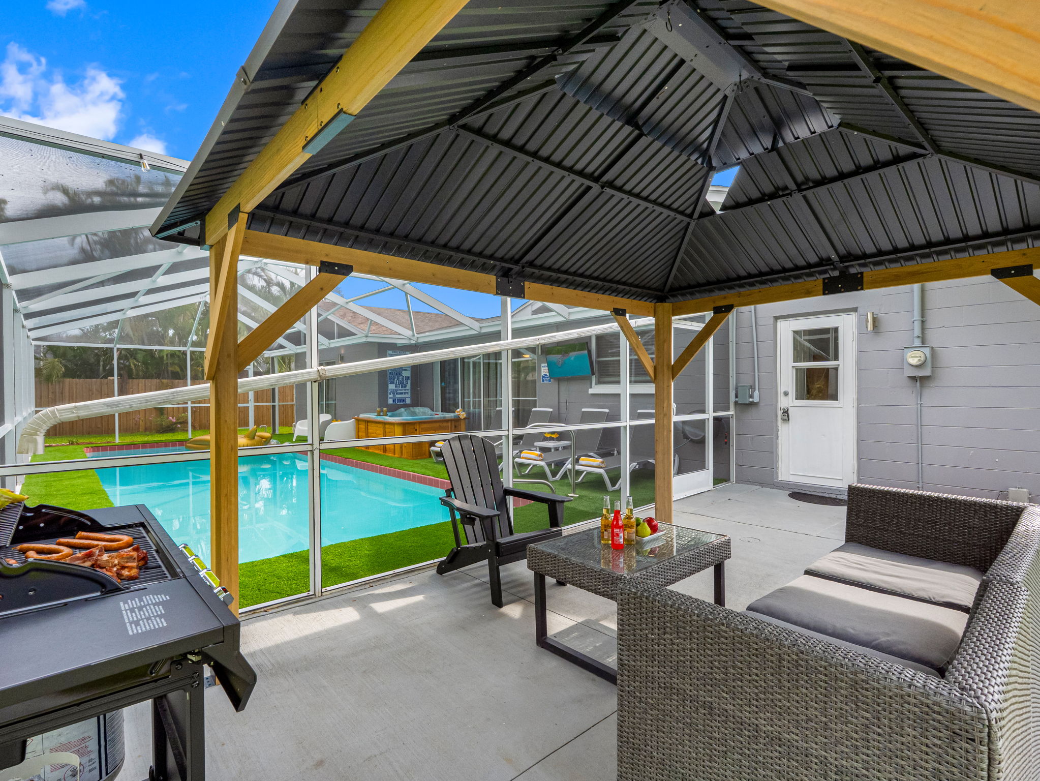 Relax in the shade under this modern gazebo, complete with cozy seating, a dining table, and easy access to the pool and spa.
