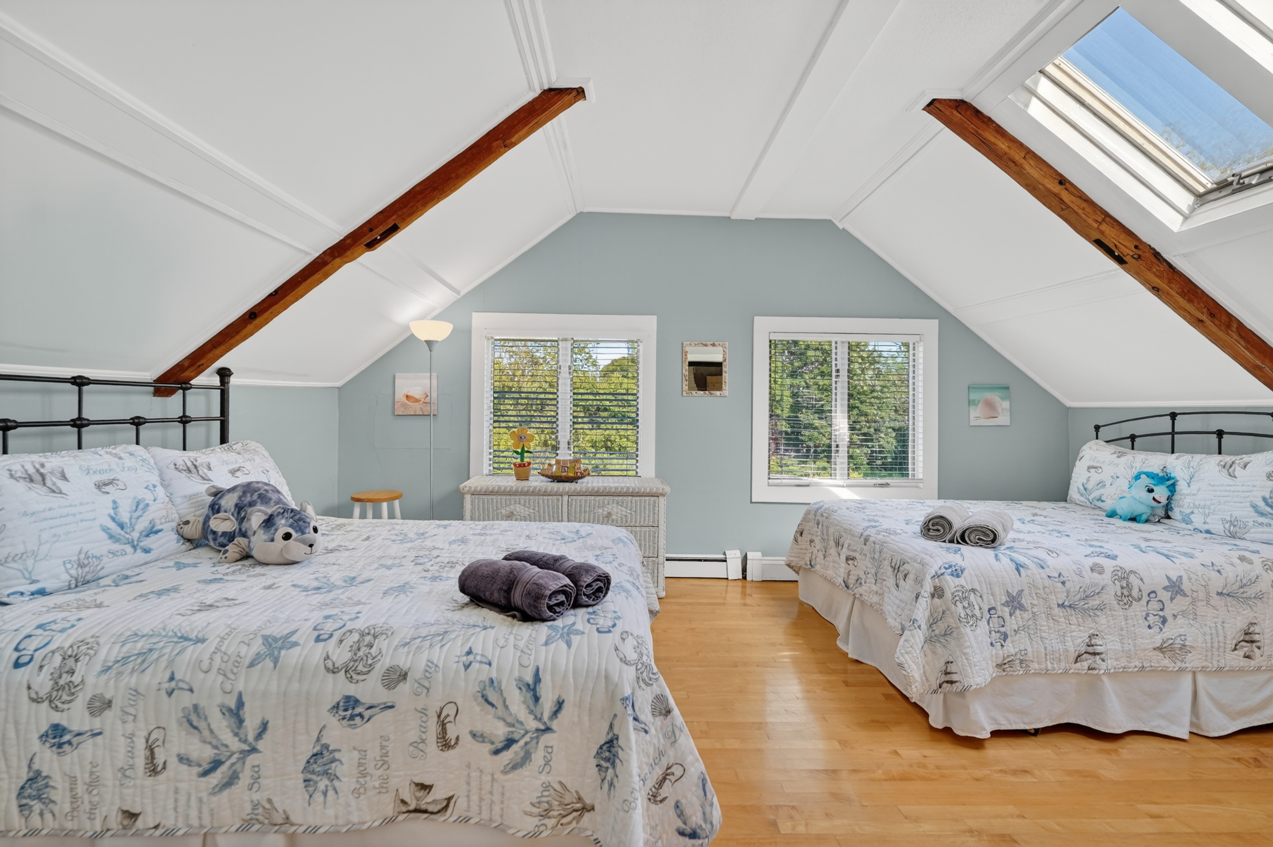 Spacious upstairs bedroom with two comfortable beds, vaulted ceilings, and plenty of natural light.