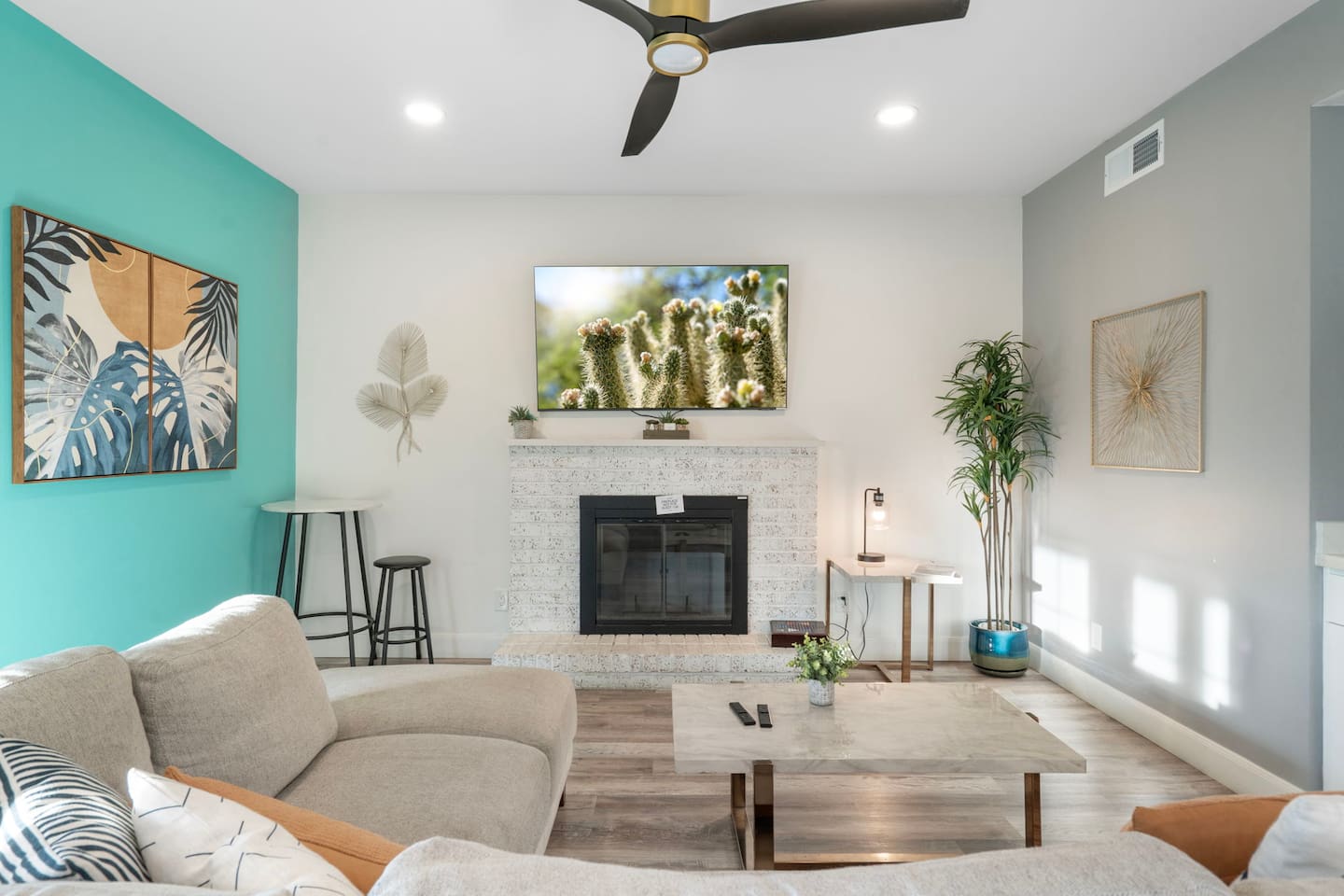 Modern living room with fireplace, smart TV, turquoise accent wall, and plenty of natural light.