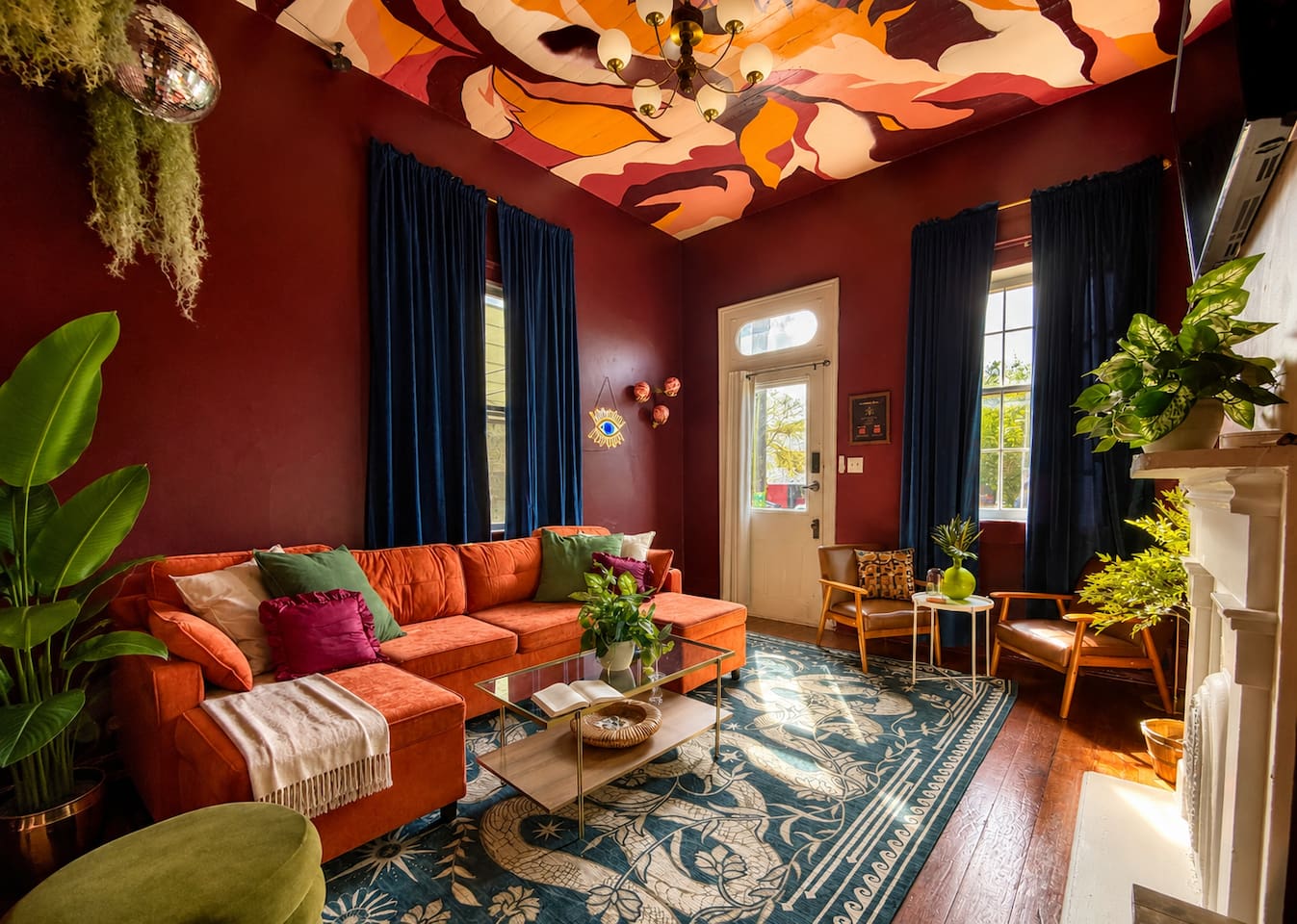 Designer living room in this unique New Orleans Airbnb near the French Quarter. Velvet sleeper sectional, dramatic ceiling mural, vintage charm, and cozy seating create the perfect lounge  before a night out on Frenchmen Street.