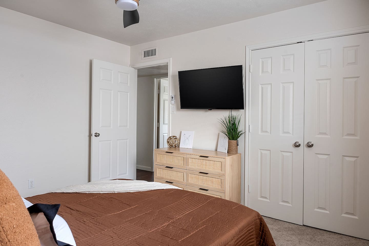 The bedroom is furnished with a sleek dresser and a wall-mounted TV, offering a modern and functional space for relaxation.