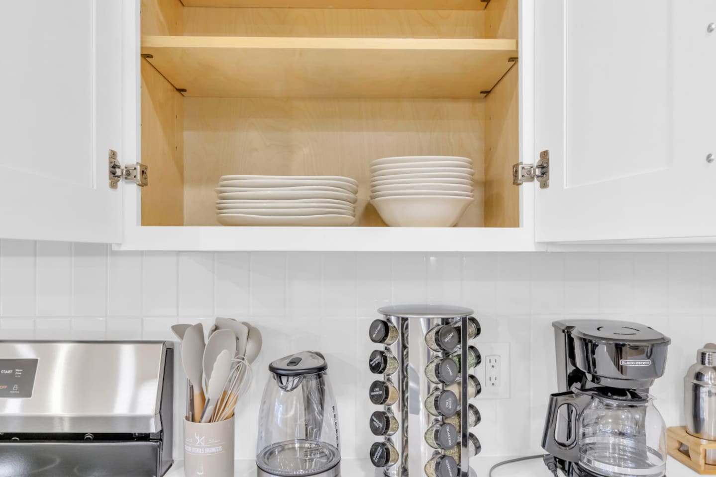 Open cabinet stocked with dishes and cutlery, bowls, and plates for group meals. Perfect for guests planning to enjoy the fully equipped kitchen.