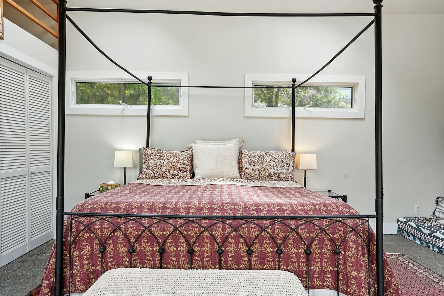 - Cozy sleeping area with elegant four poster bed and patterned quilt  
- Side windows bring in natural light while providing privacy  
- Simple decor and warm lighting make it a restful and comfortable space