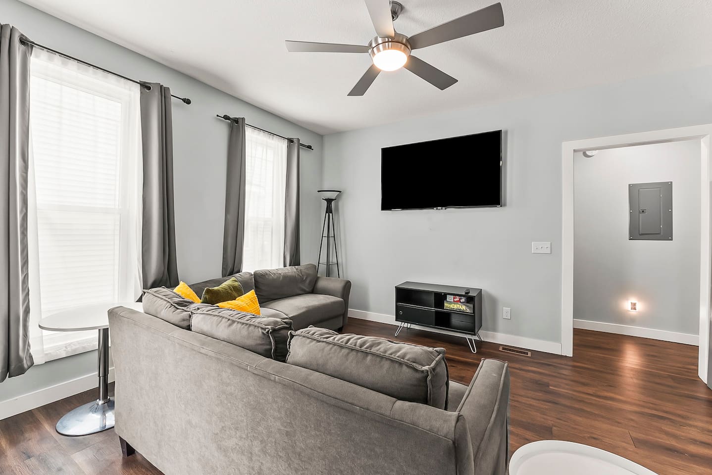 Relax in the inviting living room featuring modern lighting, hardwood floors, and a large wall-mounted TV.