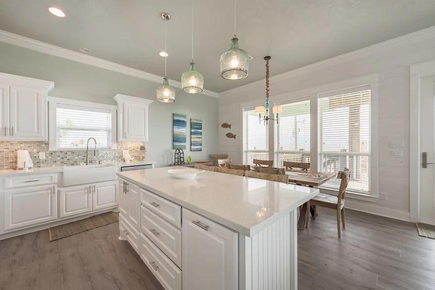 This open-concept kitchen blends contemporary stainless steel appliances with warm, natural wood textures and soft coastal colors for a relaxed yet sophisticated feel.
