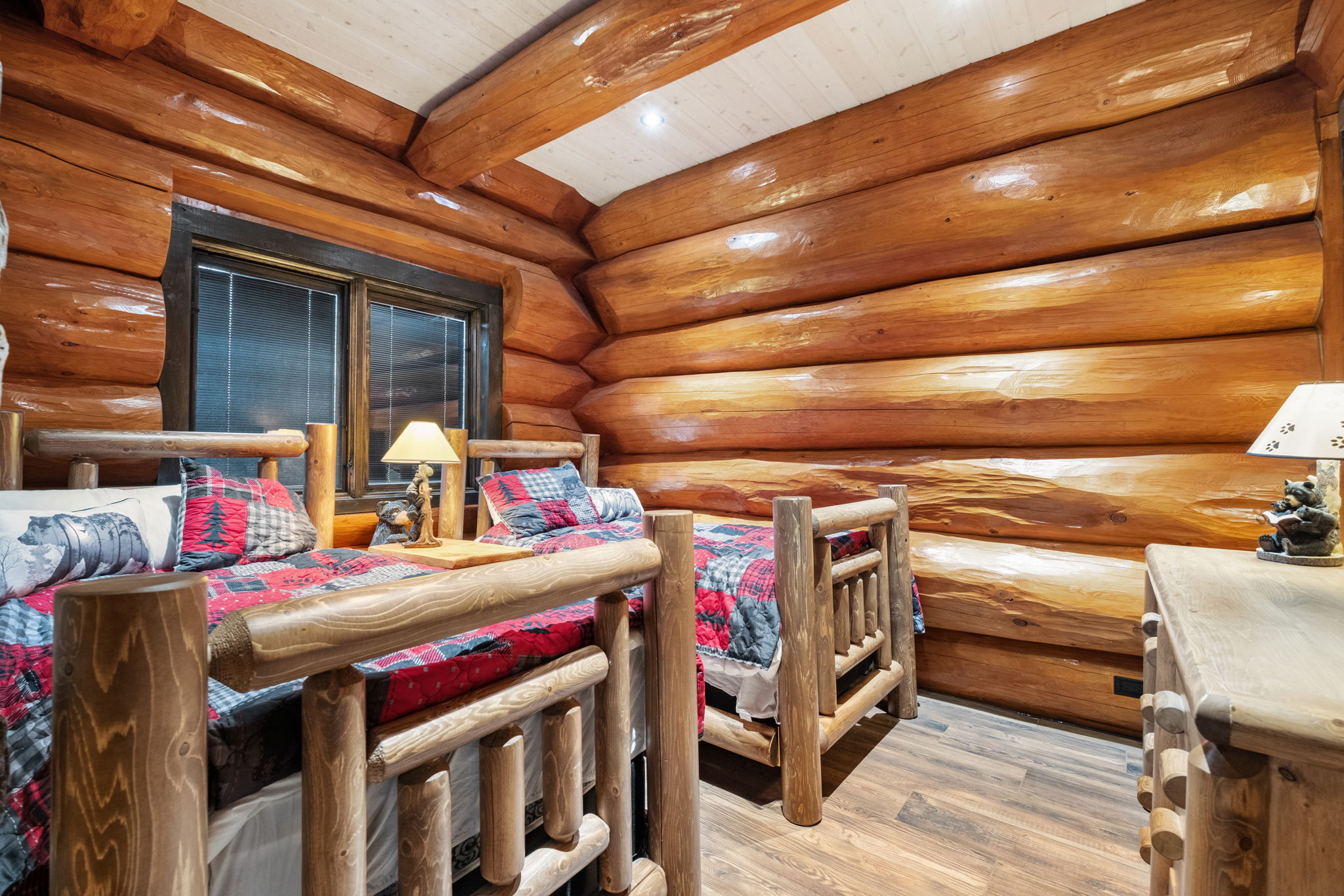 Charming twin bedroom surrounded by stunning full-log walls, cozy bedding, and warm lighting — ideal for kids or friends traveling together.