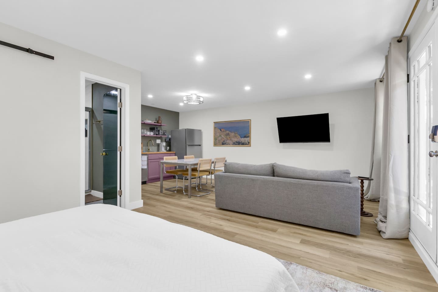 Open-concept 500 sq ft studio featuring a king bed, full kitchen, spacious couch, and TV; perfect blend of comfort and style in Dallas.