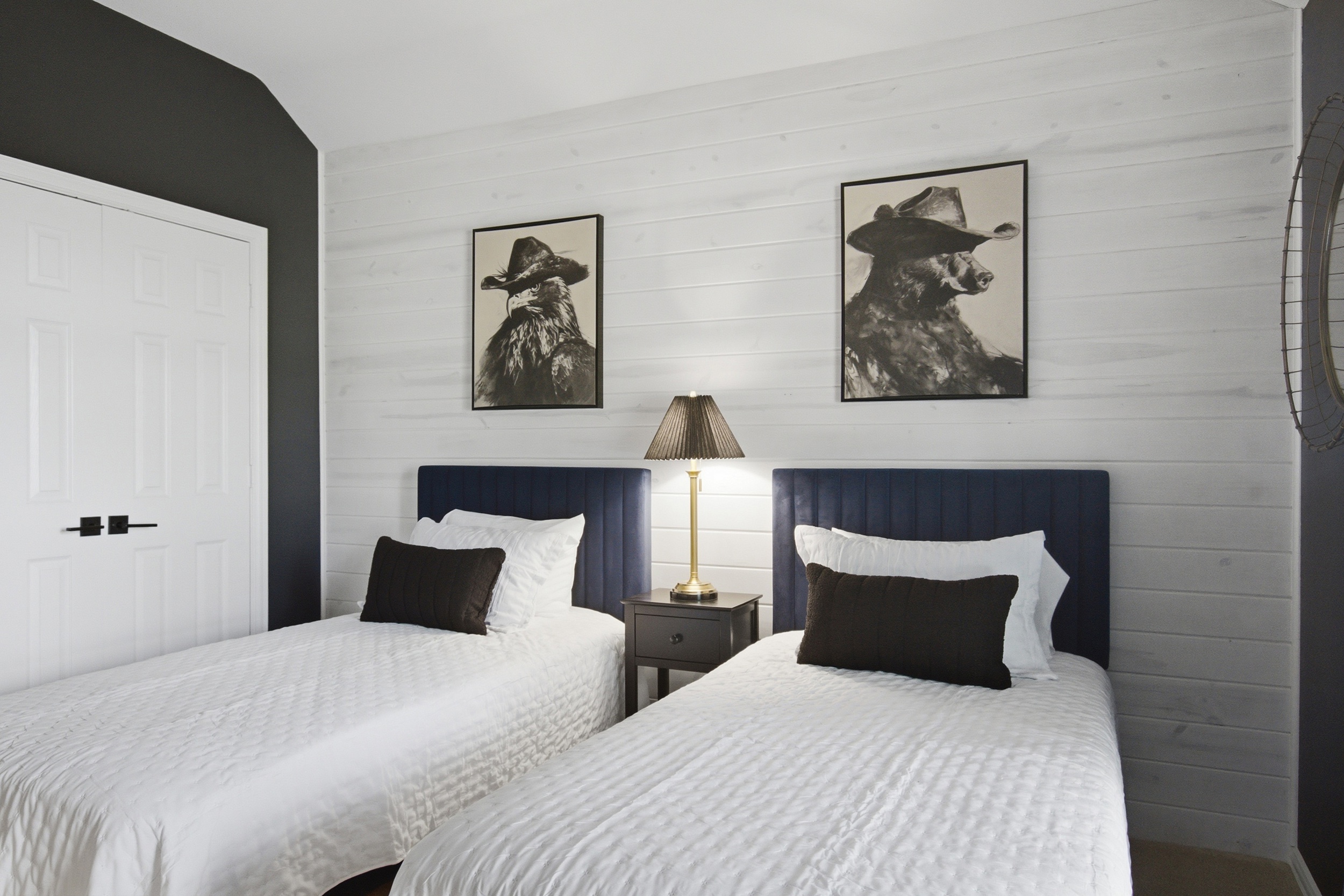 Guest Bedroom 3 featuring 2 Twin Beds with navy headboards, bedside lamp, and clean white walls. Great for siblings or a pair of friends.
