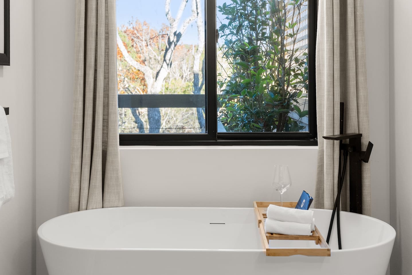 A soaking tub with outdoor view and courtains for privacy