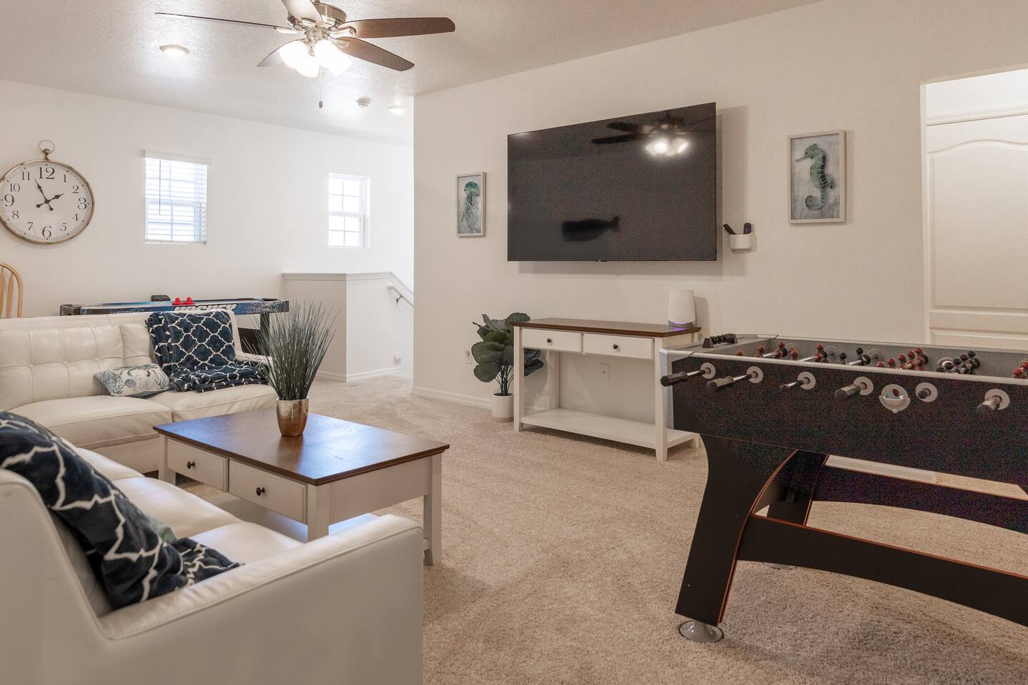 Upstairs lounge area with couch, 75in smart TV, overhead fan, air hockey table, foosball table and two player arcade game with thousands of games. 