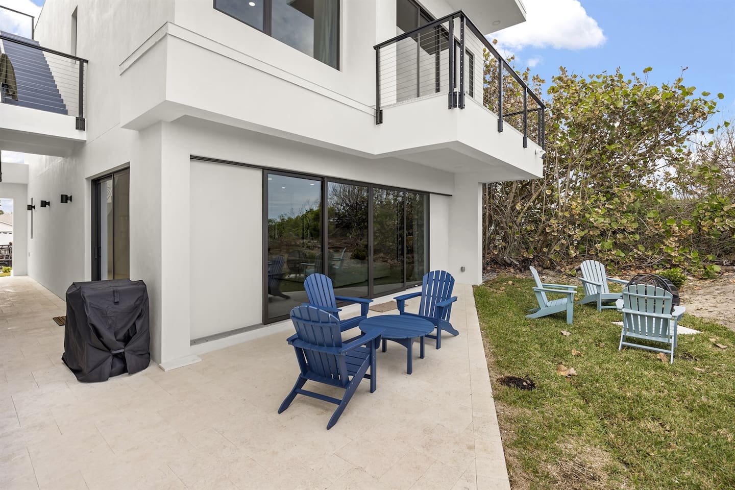 Step outside to a charming terrace with tables and chairs, surrounded by lush greenery on the other side, offering a perfect setting for relaxation, dining, or enjoying the peaceful outdoor ambiance.