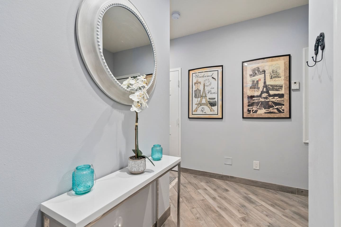 Welcoming hallway space with a decorative console table, mirror, and coastal-style artwork.