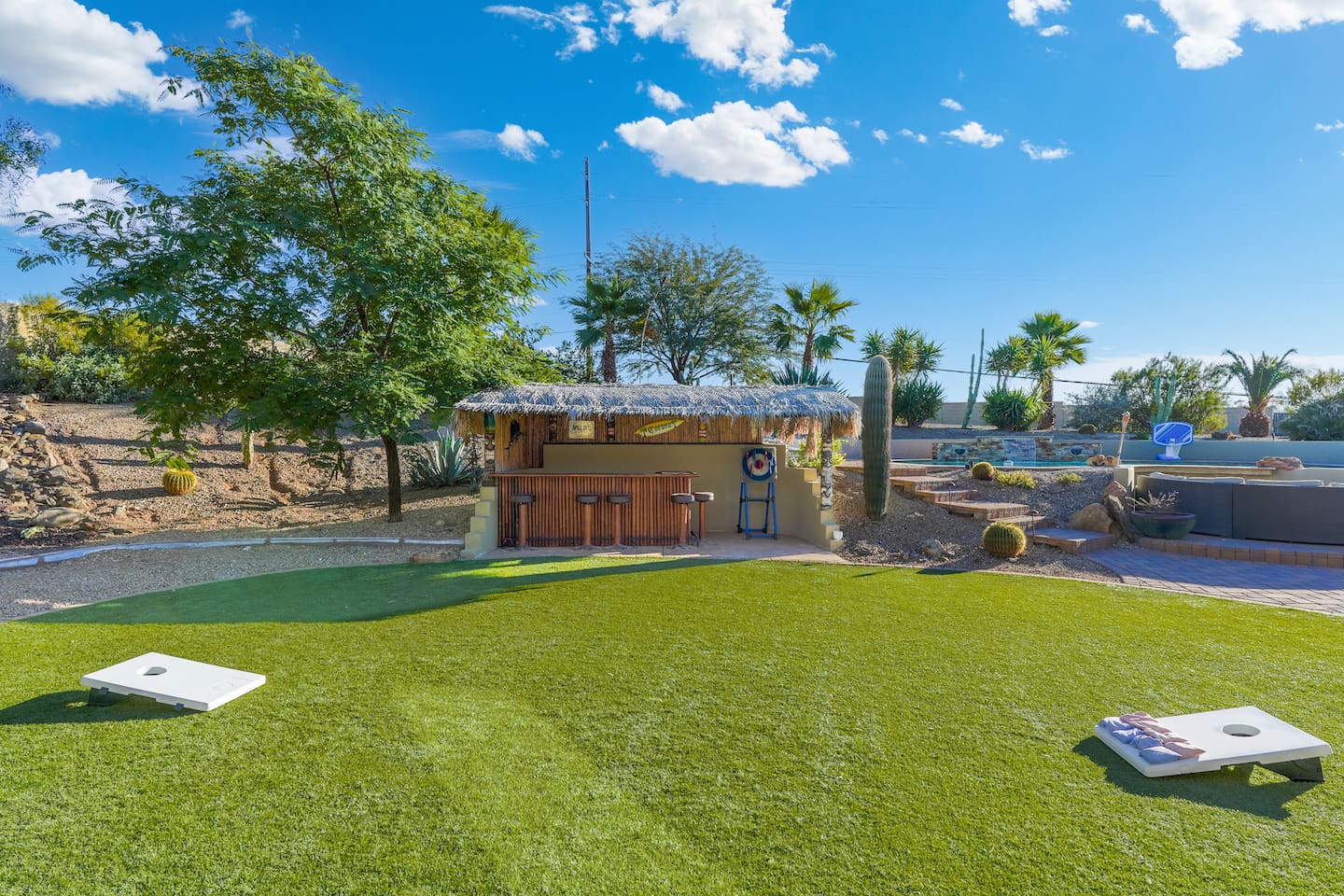 Wide view of the turf lawn with games and the tiki bar, offering plenty of space for outdoor fun.
