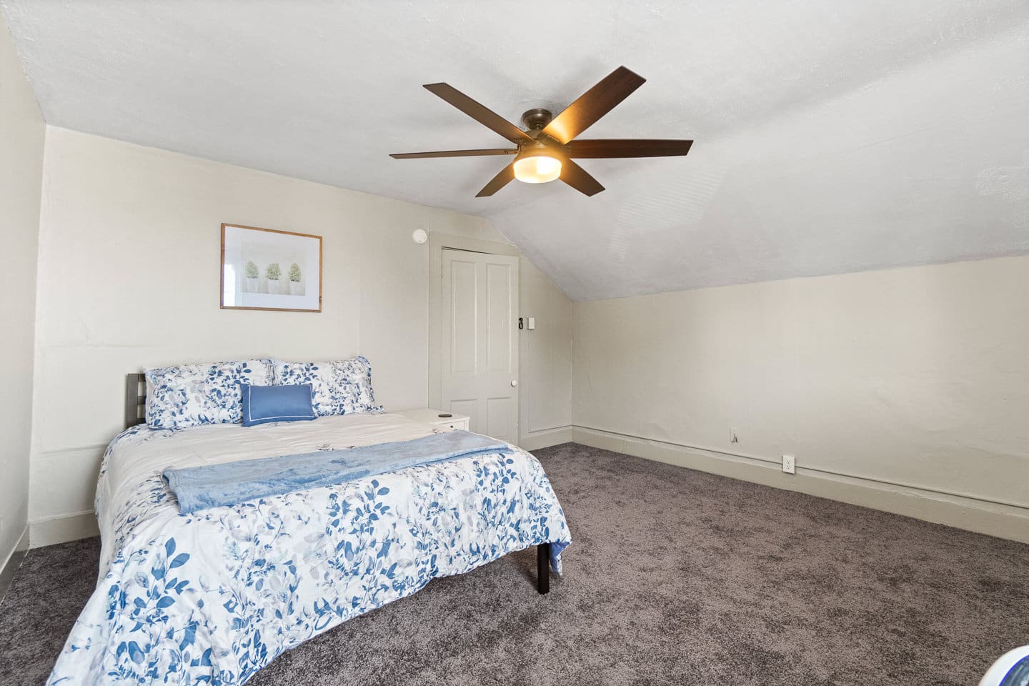 Cozy queen bedroom with plush carpet and ceiling fan.