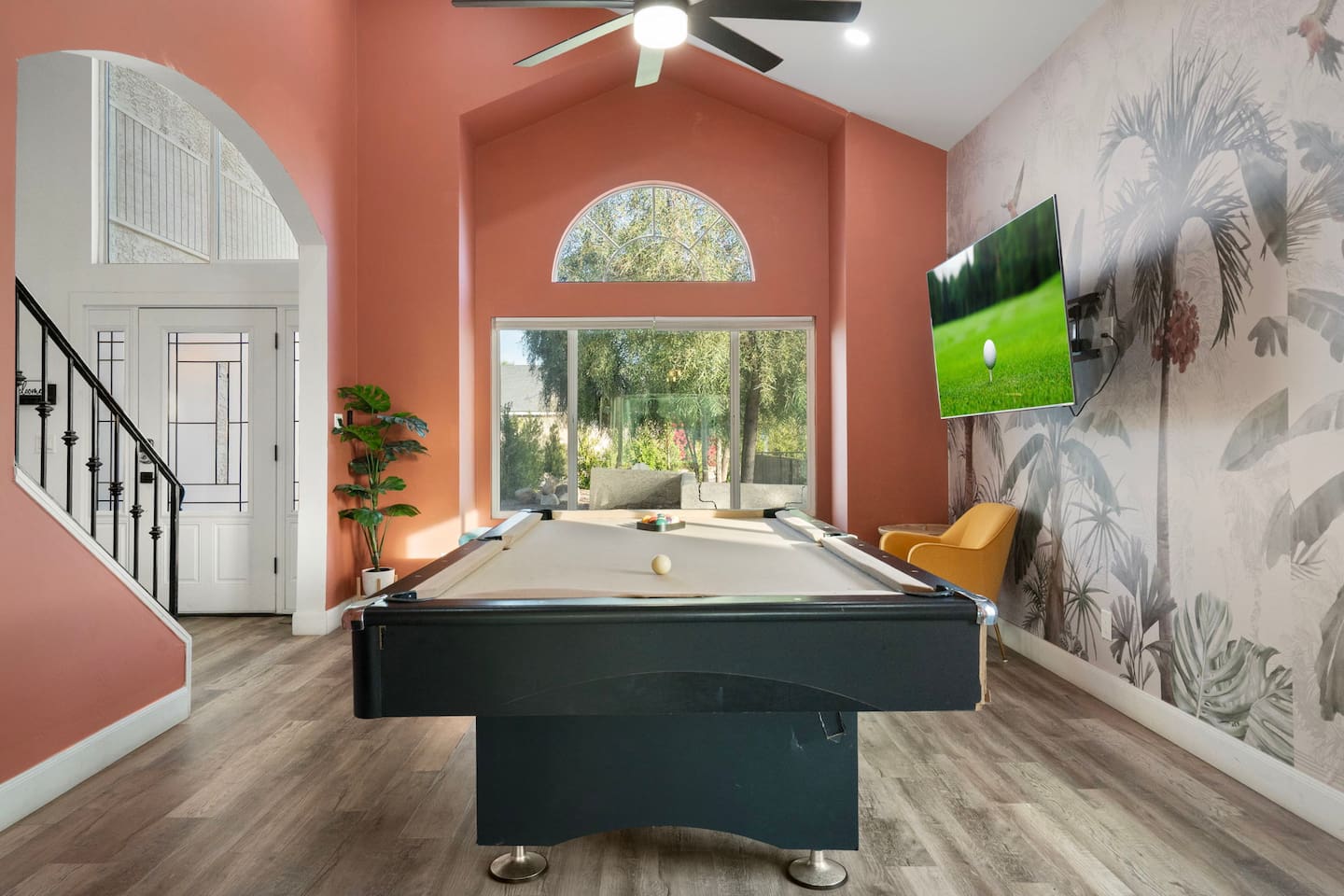 Game room with pool table, coral accent walls, botanical wallpaper, and floor-to-ceiling views.