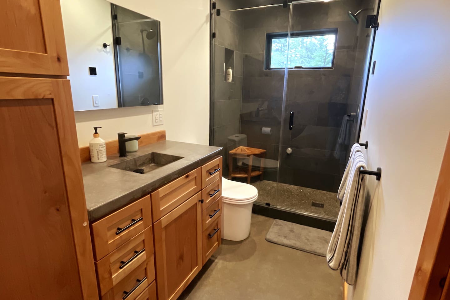 Guest bathroom with concrete counter tops, stone steam shower, lighted mirror w/defogging and pocket door to directly to guest bedroom.