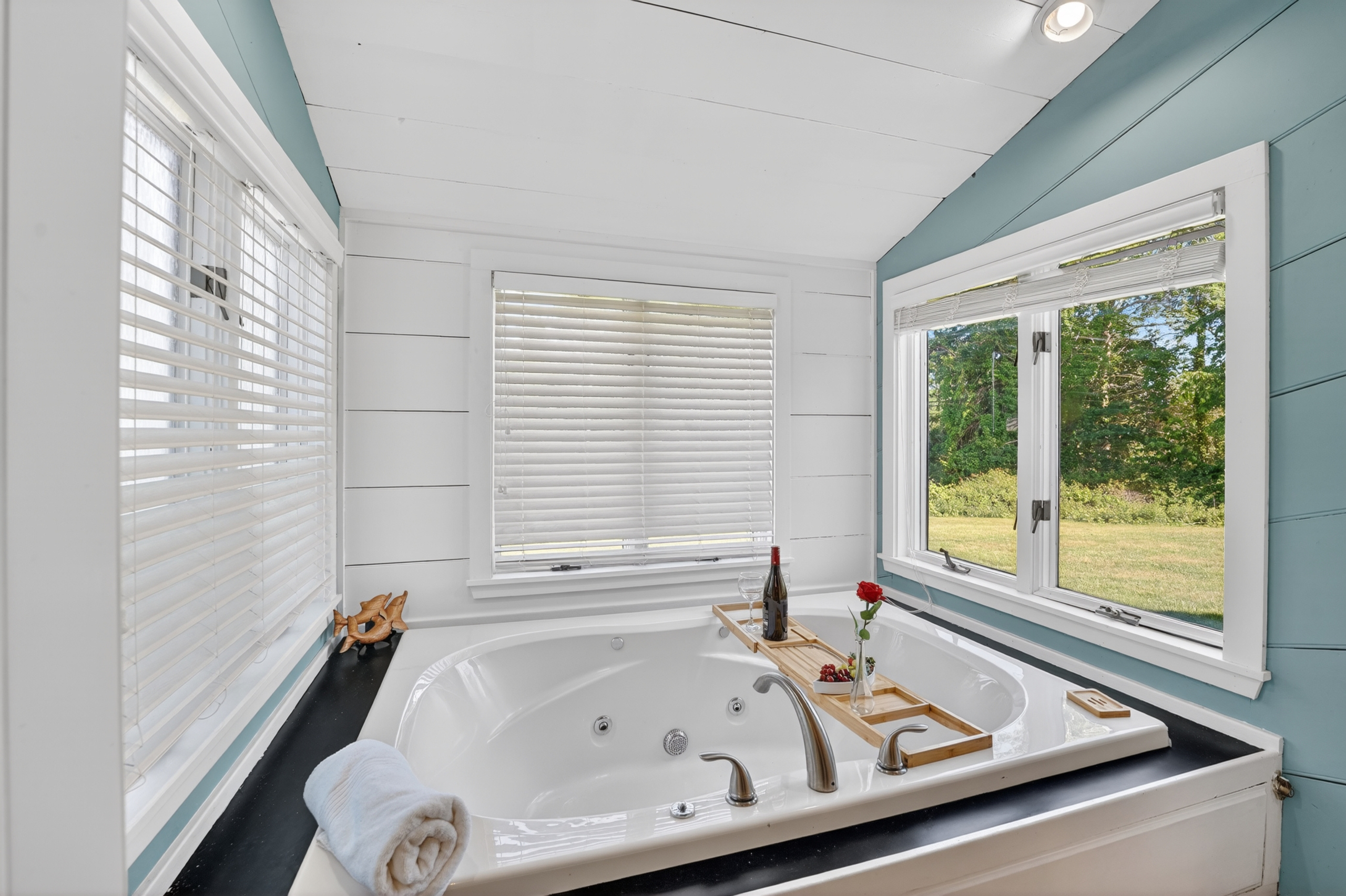 Bright bathroom featuring a relaxing soaking tub beside large windows that fill the space with natural light.